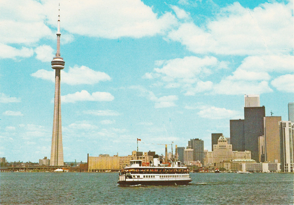 vintage postcard of the CN tower in Toronto with a ferry boat full of people in the foreground